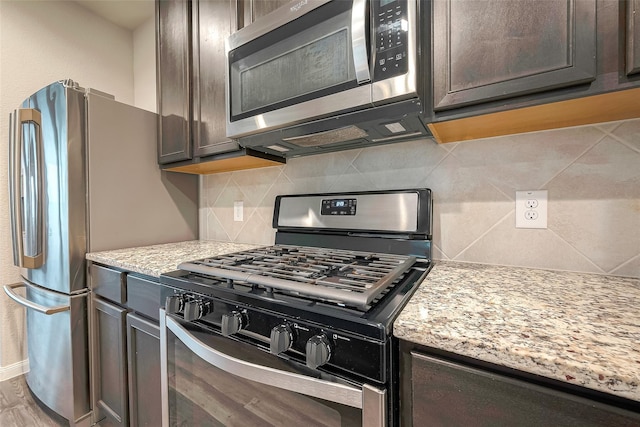 kitchen with backsplash, light stone countertops, dark brown cabinetry, and stainless steel appliances