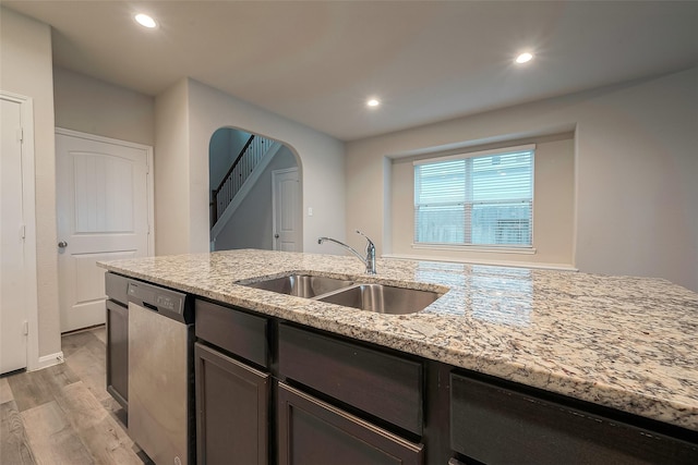 kitchen featuring dishwasher, light hardwood / wood-style floors, light stone counters, and sink