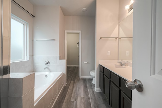 bathroom with vanity, hardwood / wood-style flooring, toilet, and tiled tub