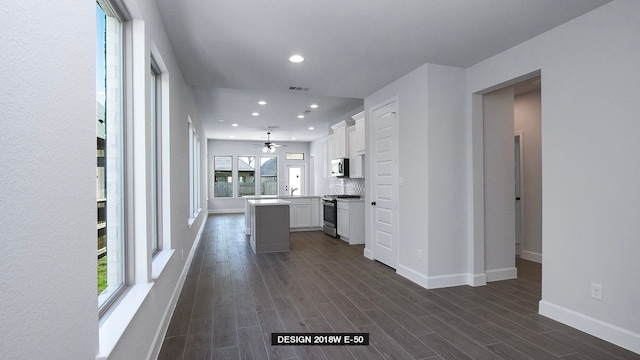 kitchen featuring stainless steel appliances, dark hardwood / wood-style floors, backsplash, white cabinets, and a center island