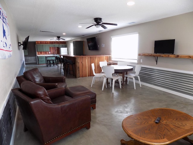 living room with ceiling fan, concrete flooring, and a textured ceiling