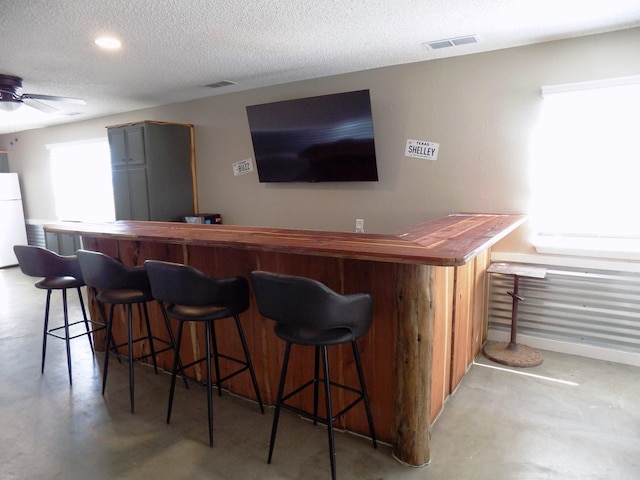 bar featuring ceiling fan, a textured ceiling, and white refrigerator