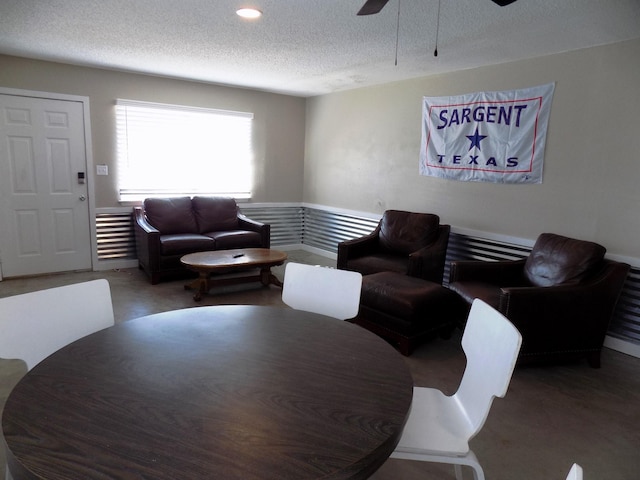 living room featuring ceiling fan and a textured ceiling