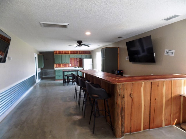 bar featuring a textured ceiling, dark carpet, and ceiling fan