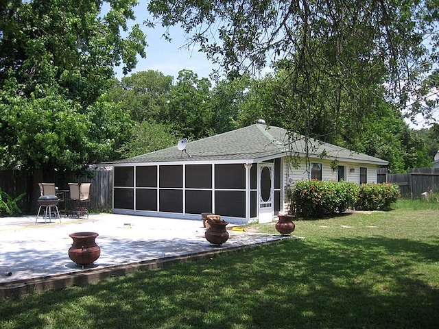 rear view of property featuring a lawn, a sunroom, and a patio