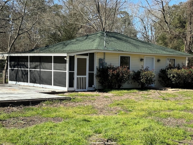 rear view of house featuring a lawn and a sunroom