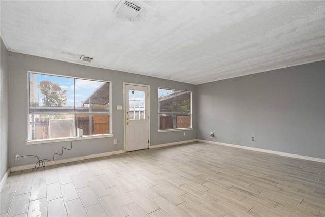 unfurnished room with light hardwood / wood-style floors and a textured ceiling