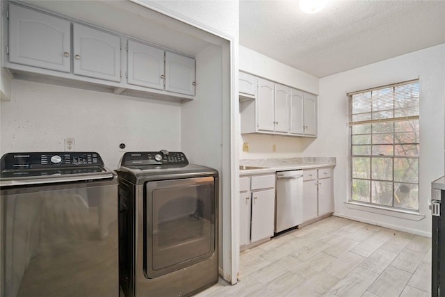 clothes washing area featuring light hardwood / wood-style flooring, cabinets, a textured ceiling, and independent washer and dryer