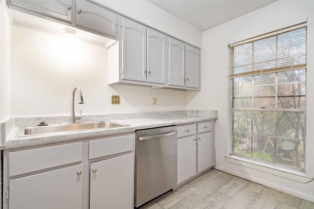 kitchen with light hardwood / wood-style flooring, stainless steel dishwasher, and sink