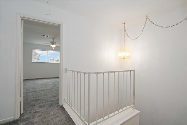 hall featuring dark colored carpet and a chandelier