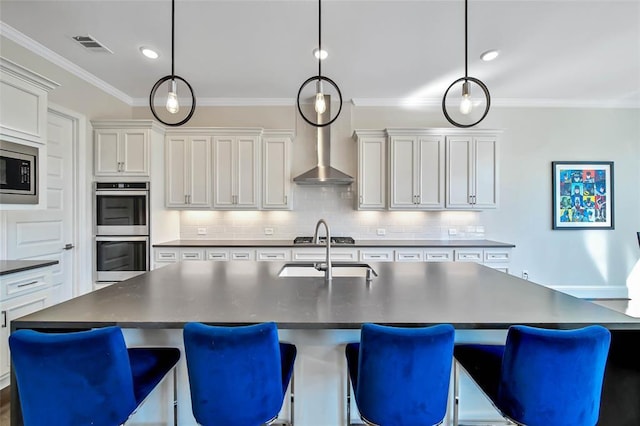 kitchen featuring sink, stainless steel appliances, hanging light fixtures, and an island with sink