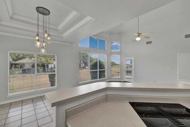 kitchen featuring light tile patterned floors, a high ceiling, ornamental molding, and black stovetop