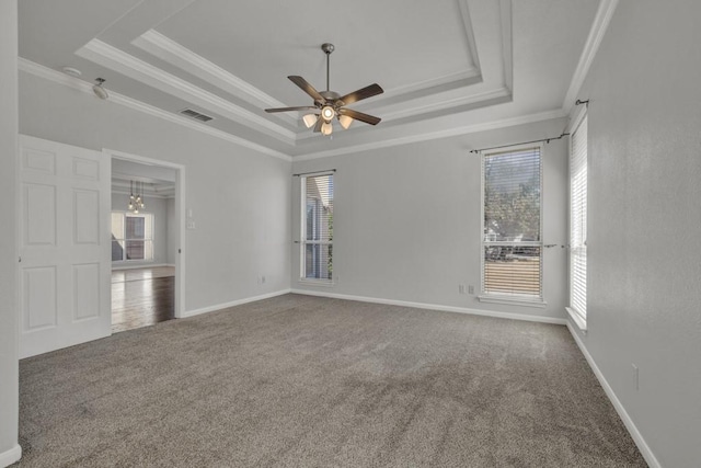 spare room featuring a tray ceiling, carpet floors, ceiling fan with notable chandelier, and ornamental molding