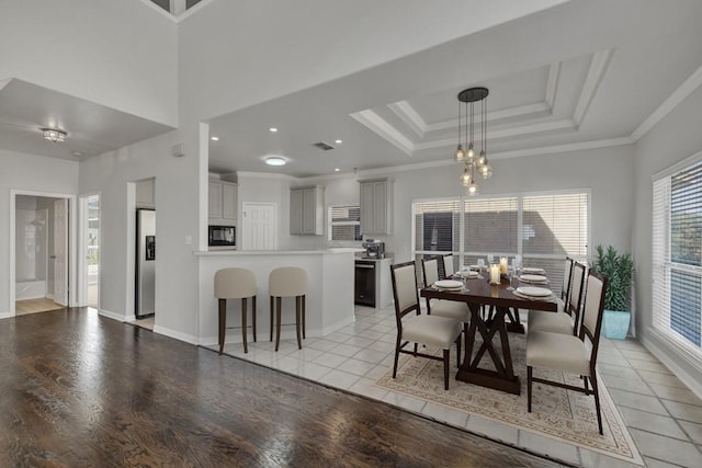 dining room featuring light hardwood / wood-style flooring, a healthy amount of sunlight, a notable chandelier, and ornamental molding