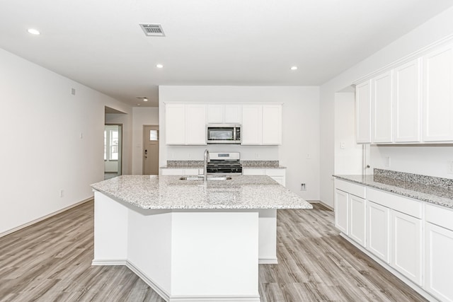 kitchen featuring light hardwood / wood-style floors, white cabinetry, stainless steel appliances, and a kitchen island with sink