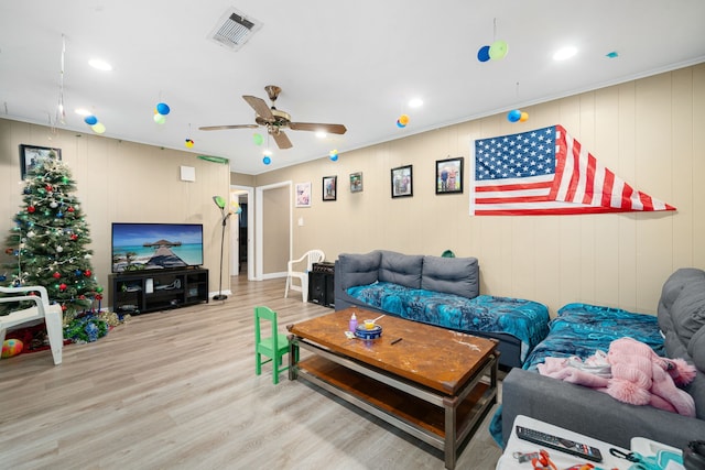 living room featuring light hardwood / wood-style floors, ceiling fan, and wooden walls