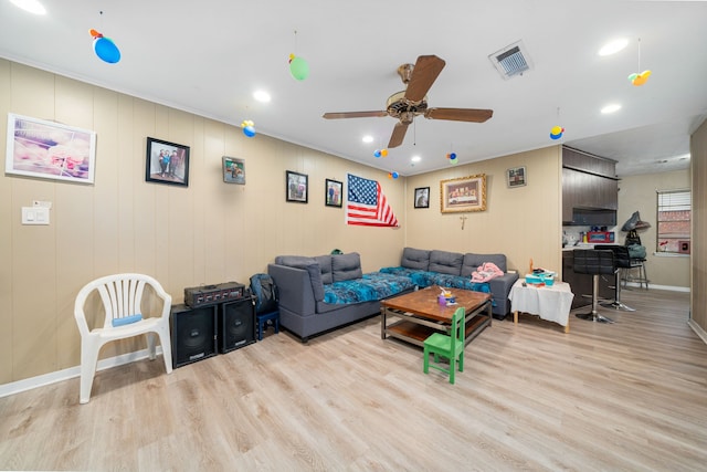 living room with ceiling fan, light wood-type flooring, and ornamental molding