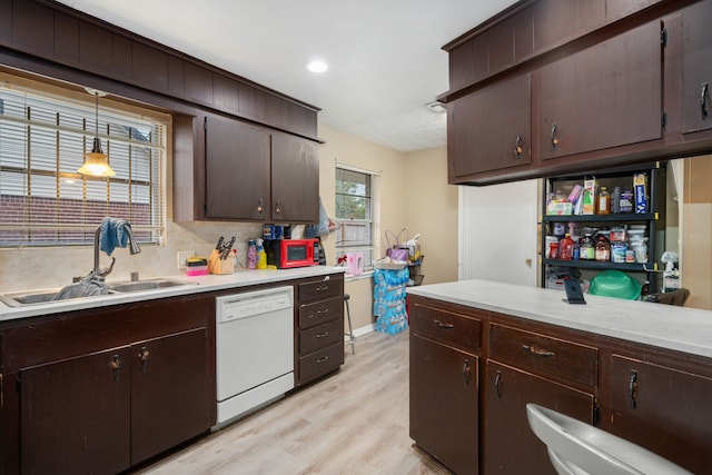 kitchen featuring decorative backsplash, light wood-type flooring, white dishwasher, sink, and hanging light fixtures