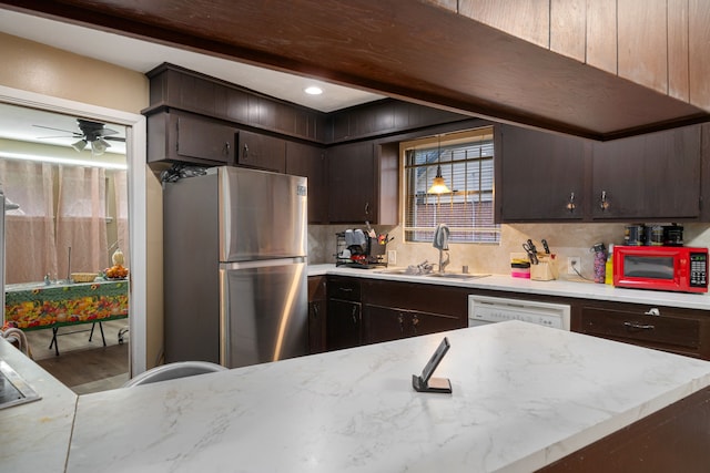 kitchen with dark brown cabinetry, white dishwasher, sink, hardwood / wood-style flooring, and stainless steel refrigerator