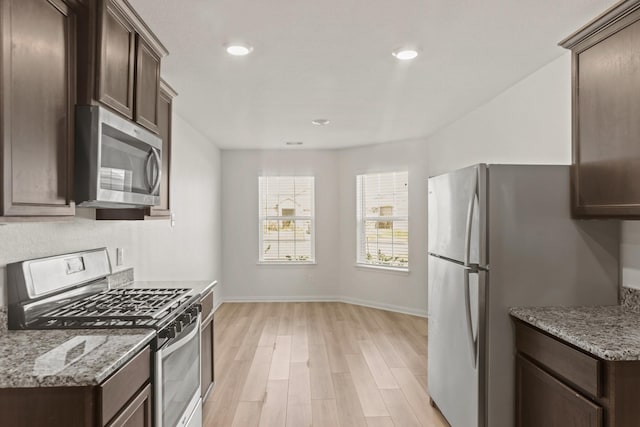 kitchen with light stone counters, dark brown cabinetry, appliances with stainless steel finishes, and light hardwood / wood-style flooring