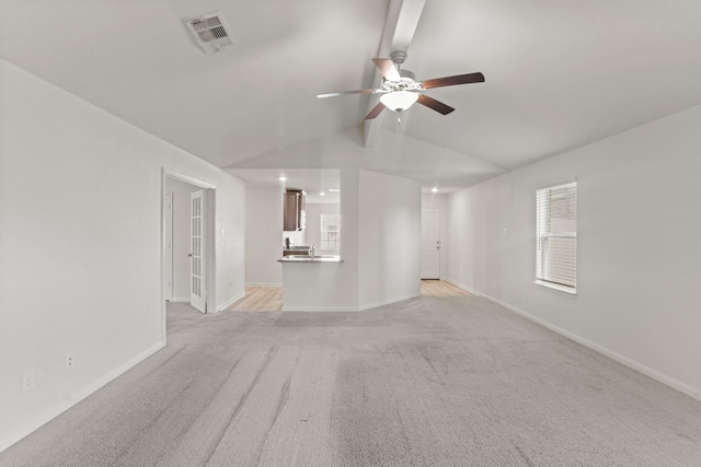 unfurnished living room with light colored carpet, vaulted ceiling, and ceiling fan