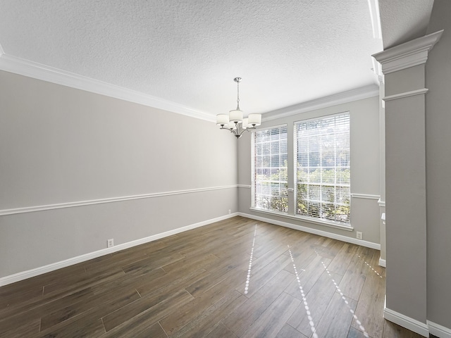 spare room with a notable chandelier, dark hardwood / wood-style flooring, a textured ceiling, and crown molding