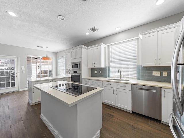 kitchen with white cabinets, sink, appliances with stainless steel finishes, and dark wood-type flooring