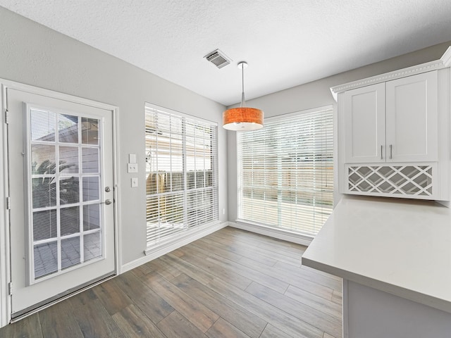 unfurnished dining area with a textured ceiling and light hardwood / wood-style flooring