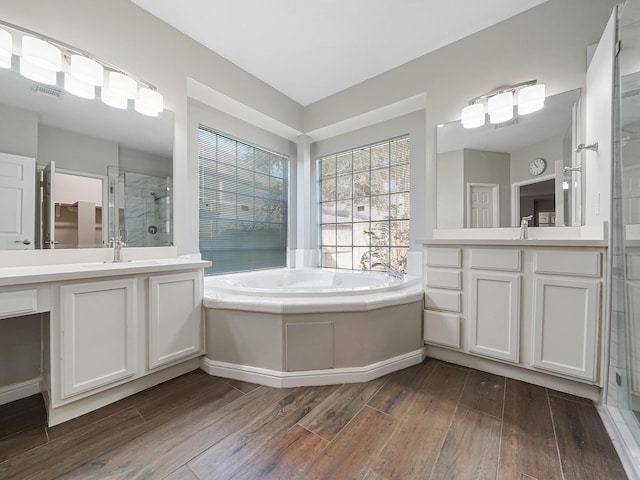 bathroom with wood-type flooring, vanity, and independent shower and bath