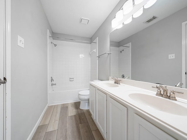 full bathroom featuring hardwood / wood-style flooring, tiled shower / bath combo, toilet, and vanity