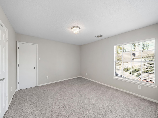 unfurnished room with carpet floors and a textured ceiling