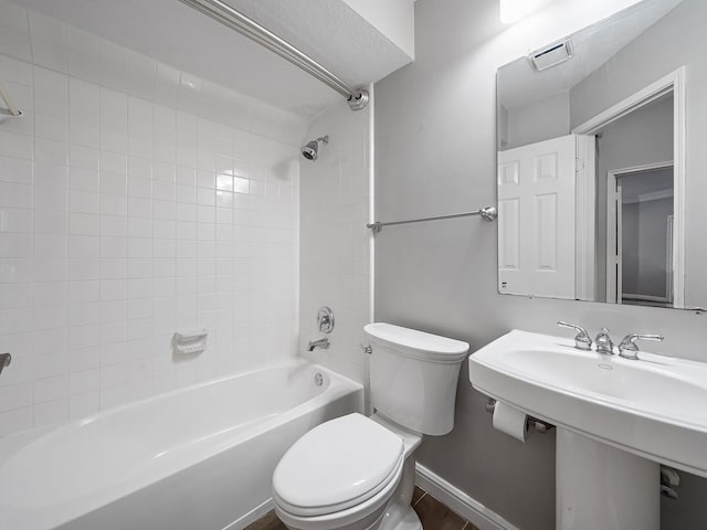 bathroom featuring toilet, wood-type flooring, and tiled shower / bath