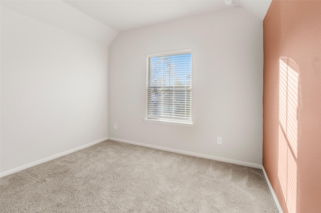 spare room featuring lofted ceiling, baseboards, and carpet