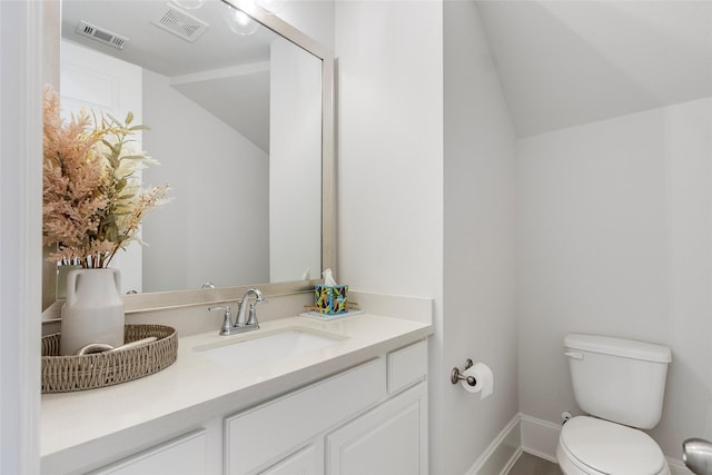 half bath featuring toilet, vaulted ceiling, vanity, and visible vents