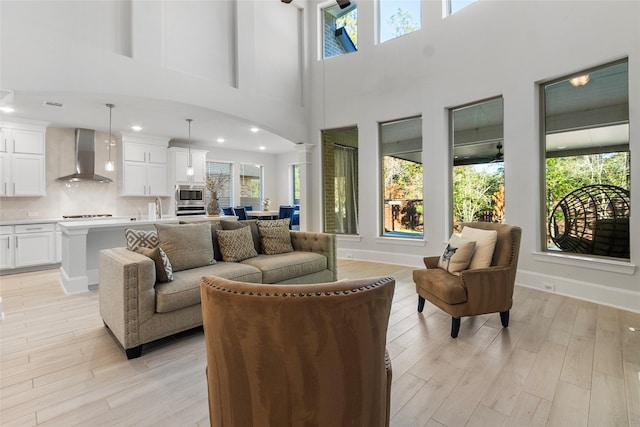 living area featuring light wood finished floors, decorative columns, arched walkways, baseboards, and recessed lighting