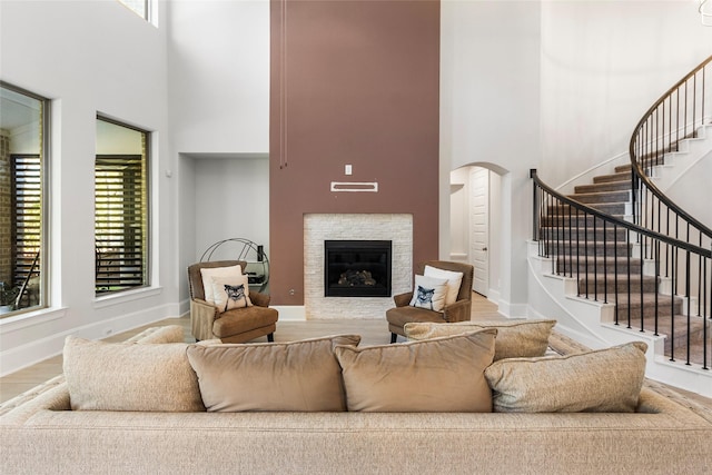 living area with a towering ceiling, stairway, and a glass covered fireplace