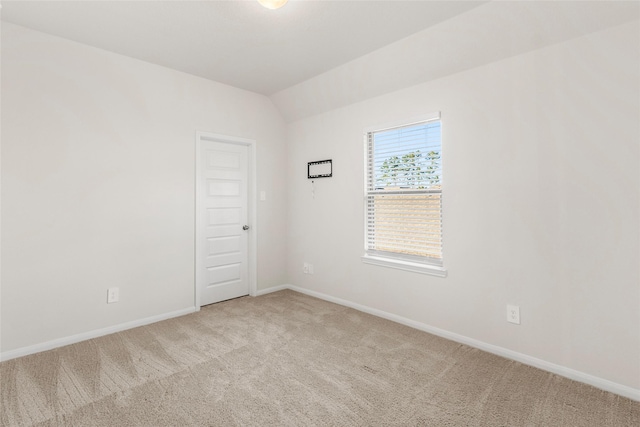 unfurnished room with lofted ceiling, light carpet, and baseboards