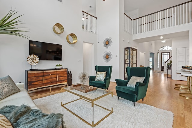 living room featuring light wood-type flooring and a high ceiling