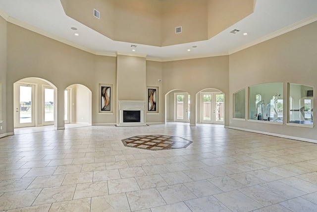 unfurnished living room with plenty of natural light, ornamental molding, a high ceiling, and french doors