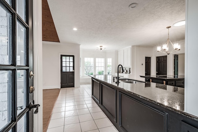 kitchen with white cabinets, sink, pendant lighting, light tile patterned floors, and a chandelier