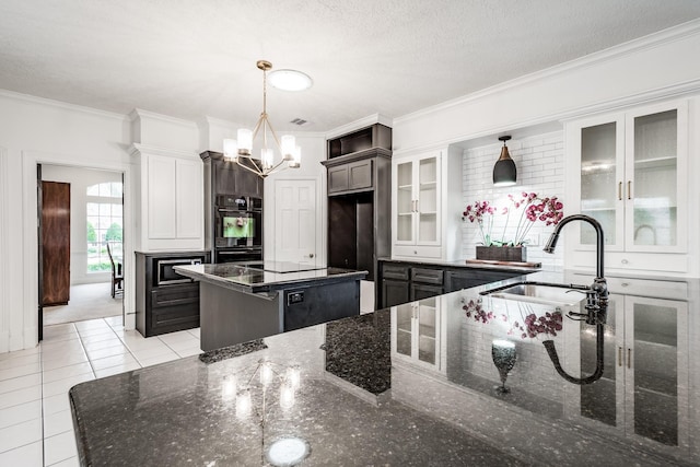 kitchen featuring sink, decorative light fixtures, dark stone countertops, a center island, and light tile patterned flooring