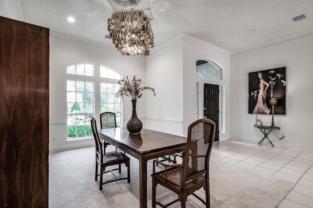 dining room with a chandelier, light tile patterned floors, a textured ceiling, and ornamental molding