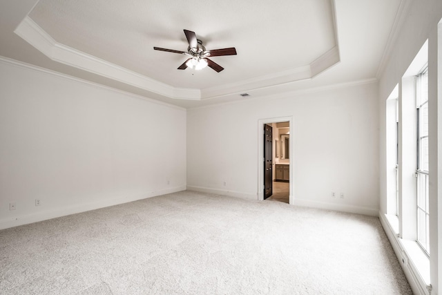 carpeted spare room featuring a raised ceiling, ceiling fan, and ornamental molding