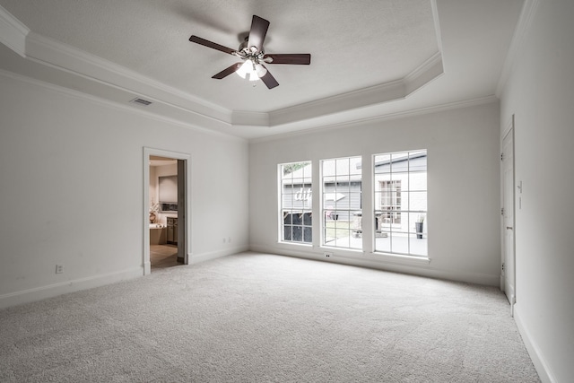 empty room with ceiling fan, a raised ceiling, ornamental molding, and carpet floors