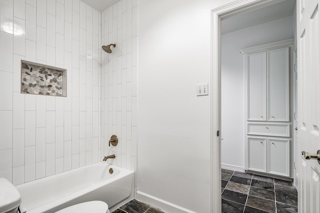 bathroom featuring tiled shower / bath combo and toilet