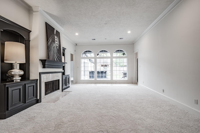 unfurnished living room featuring a tile fireplace, a textured ceiling, light colored carpet, and ornamental molding