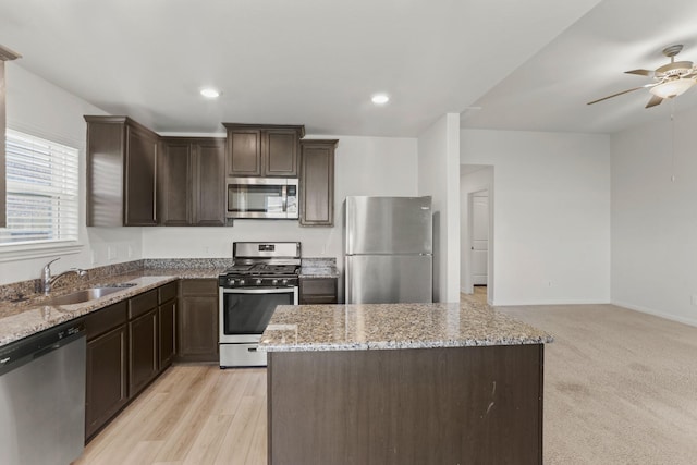 kitchen featuring light stone countertops, sink, stainless steel appliances, and light wood-type flooring