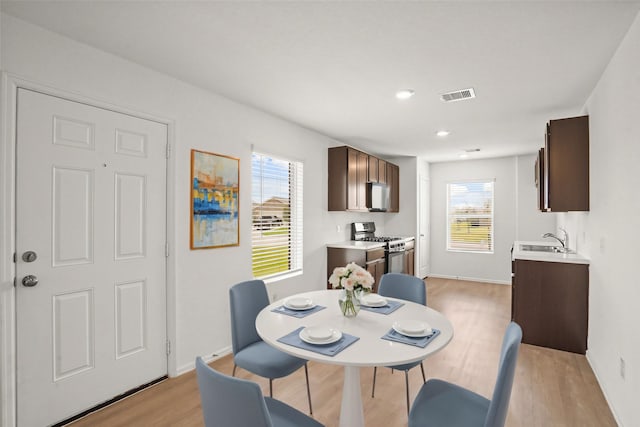 dining space featuring light wood-type flooring, plenty of natural light, and sink