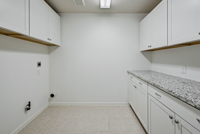 washroom with electric dryer hookup, light tile patterned flooring, and cabinets