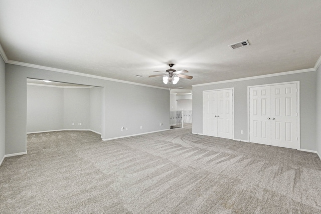 unfurnished bedroom featuring multiple closets, ceiling fan, crown molding, and carpet floors